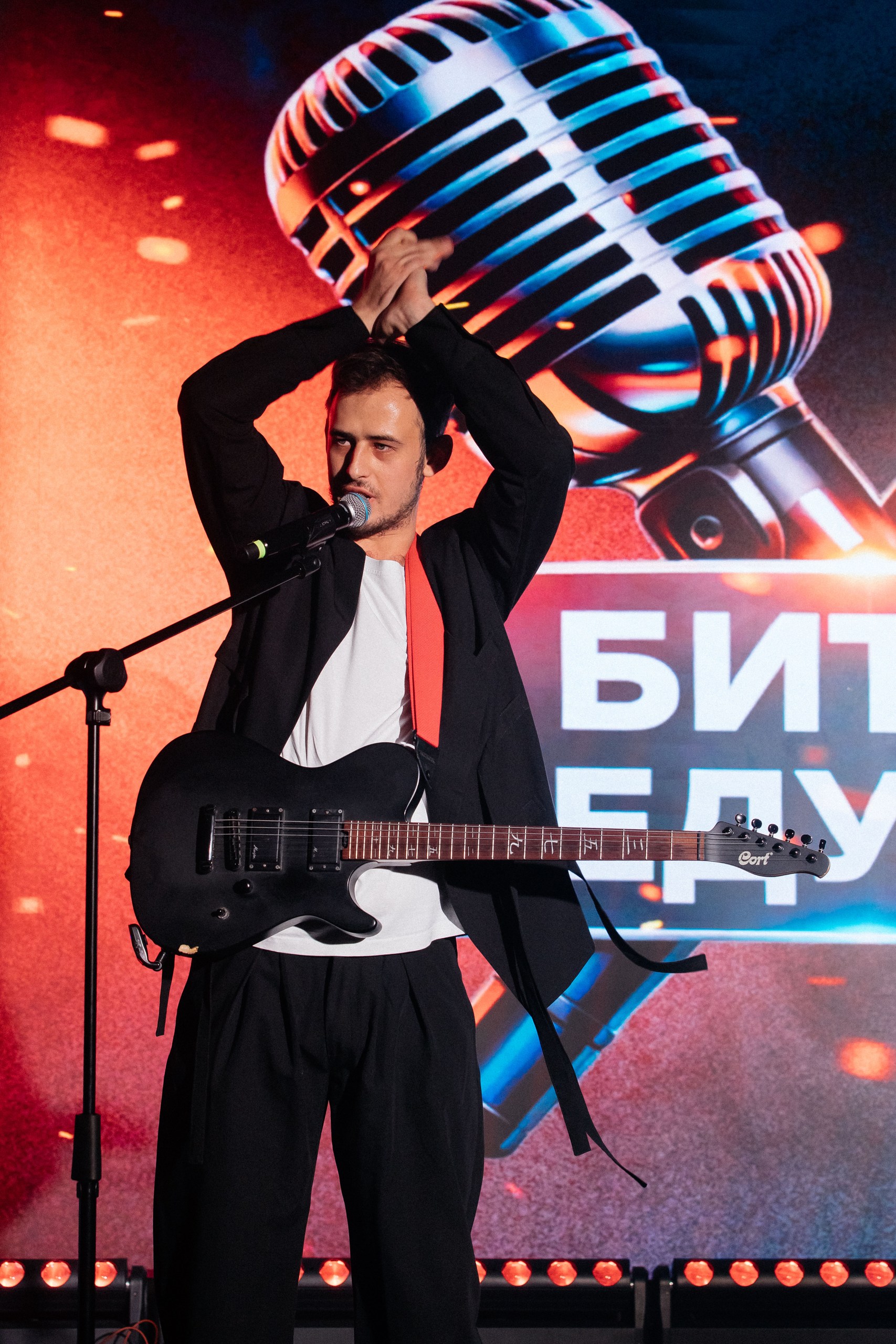 Алексей Иванов у микрофона с гитарой на сцене
